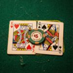 초록색 펠트 카지노 테이블 위에 나란히 놓인 킹과 퀸 카드, 그 위에 포커 칩 하나가 얹혀 있는 모습이다.