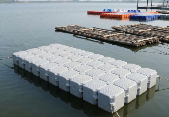 고요한 물 위에 떠 있는 단순한 플랫폼이 보이며, 배경에는 고대 뗏목과 현대식 부교가 모듈식 설계와 함께